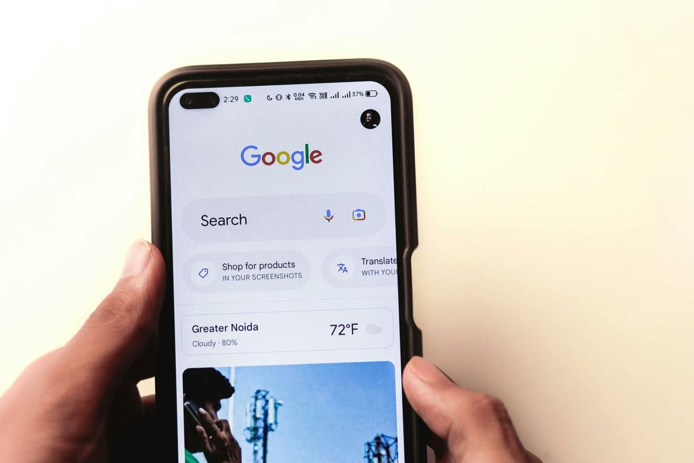 Hand holding a smartphone showing Google search